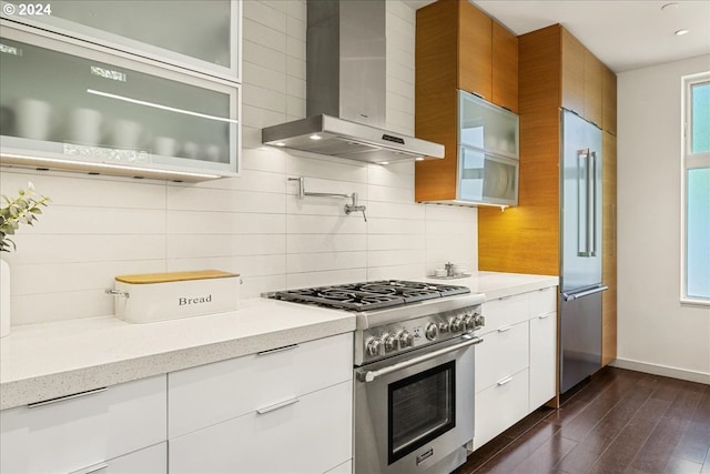 kitchen featuring backsplash, dark hardwood / wood-style flooring, high end appliances, white cabinetry, and wall chimney range hood