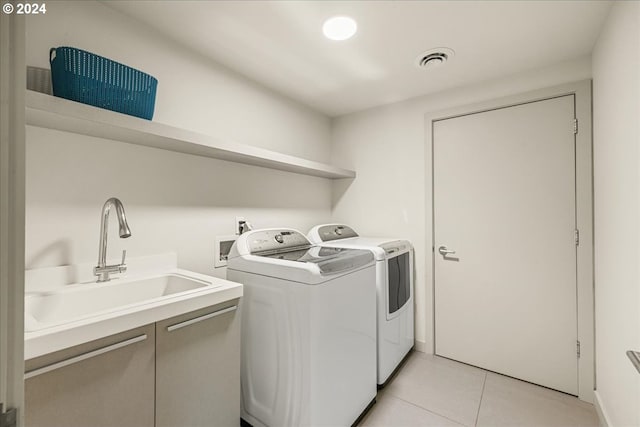 washroom with sink, washing machine and dryer, and light tile patterned floors