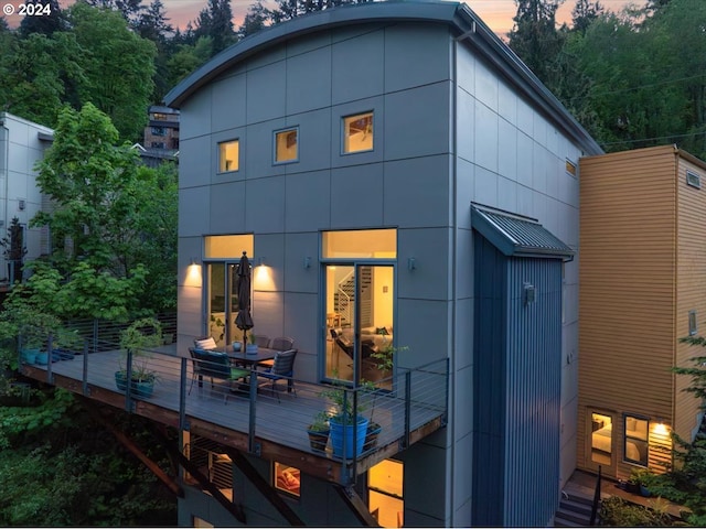 back house at dusk featuring a deck