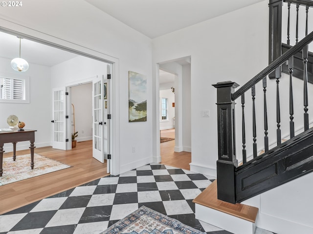 foyer featuring french doors, a wealth of natural light, and wood-type flooring