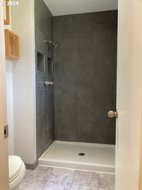 bathroom with tiled shower and toilet