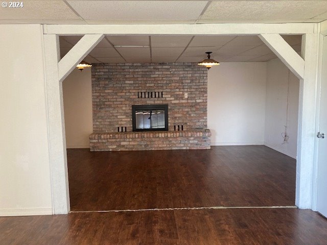 unfurnished living room featuring dark hardwood / wood-style flooring, a fireplace, and a paneled ceiling