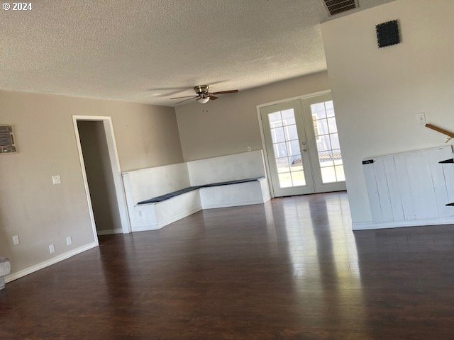 unfurnished room featuring dark hardwood / wood-style flooring, ceiling fan, french doors, and a textured ceiling