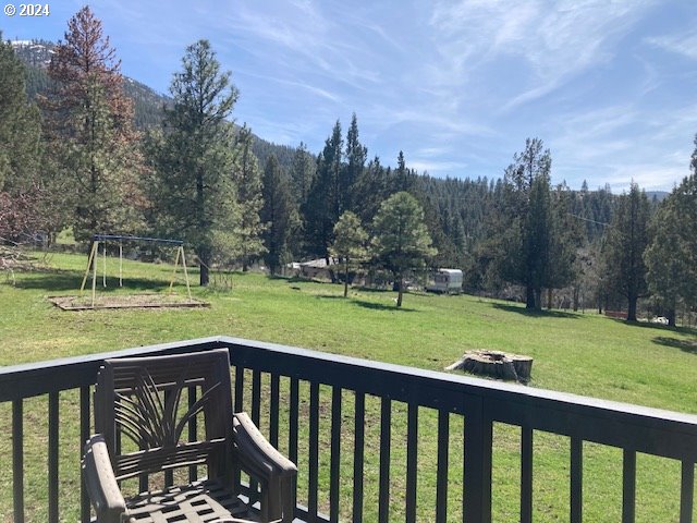 view of yard featuring a playground, a deck, and an outdoor fire pit