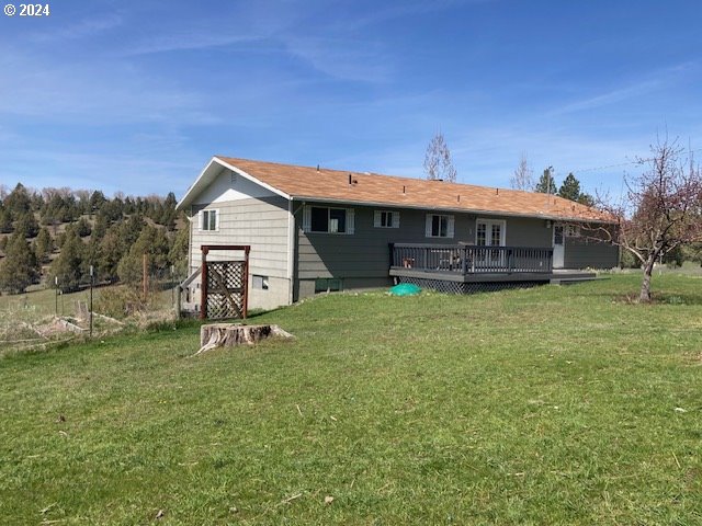 rear view of property with a deck and a lawn