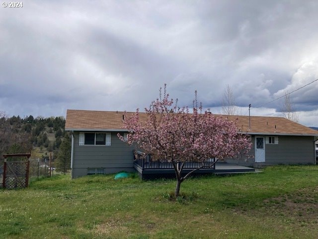 rear view of property featuring a lawn and a deck