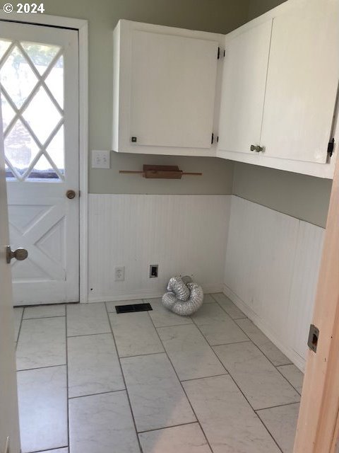 laundry area with electric dryer hookup and cabinets