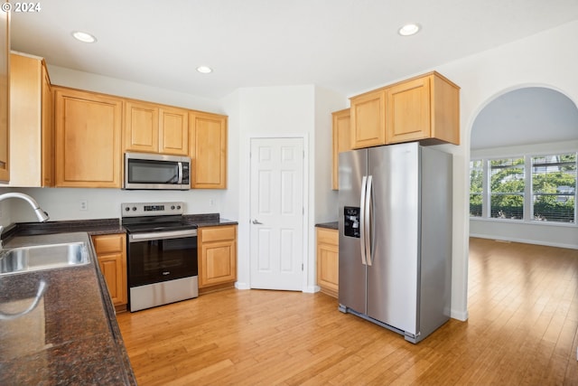 kitchen with appliances with stainless steel finishes, sink, and light hardwood / wood-style floors