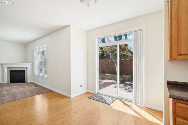 unfurnished living room with a wealth of natural light, light hardwood / wood-style flooring, and a tiled fireplace