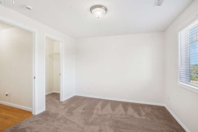 unfurnished bedroom featuring a closet, a spacious closet, and light hardwood / wood-style flooring