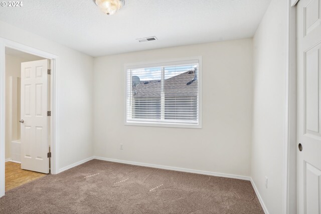 carpeted spare room with a textured ceiling