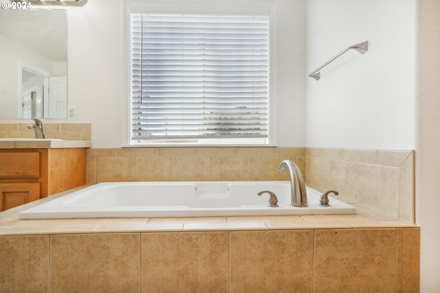 bathroom featuring tiled bath and vanity