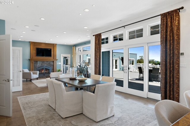 dining space with light tile patterned floors, a fireplace, and french doors