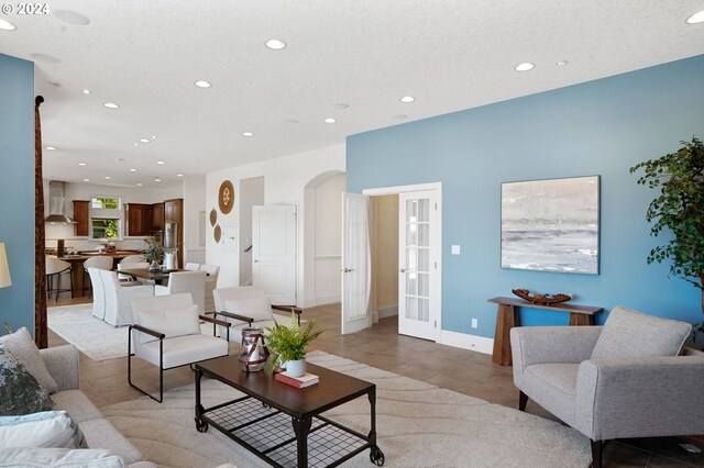 living room featuring a textured ceiling, light tile patterned floors, and french doors