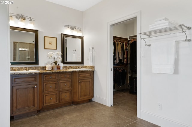 bathroom featuring double vanity, tile patterned floors, a walk in closet, and a sink