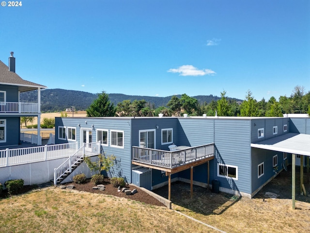 rear view of property featuring a lawn, a deck with mountain view, and stairs