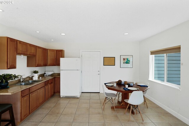 kitchen with light tile patterned floors, sink, and white fridge