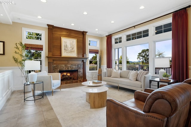 living room featuring a wainscoted wall, recessed lighting, a high end fireplace, crown molding, and a decorative wall