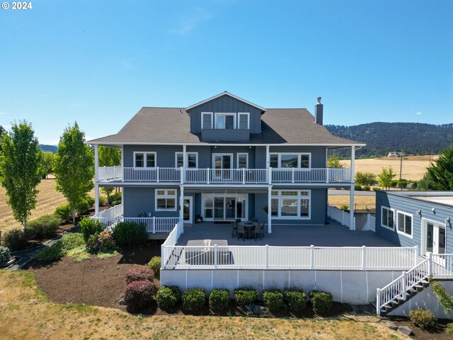 rear view of property with a balcony, a mountain view, and a patio area