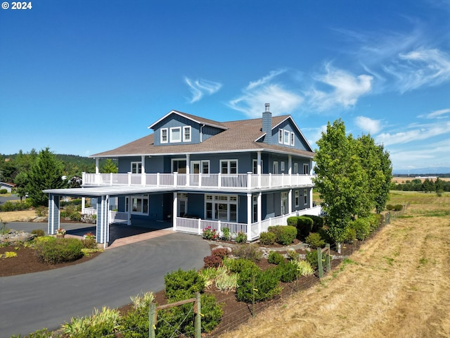 rear view of property featuring a chimney, a balcony, a porch, and driveway