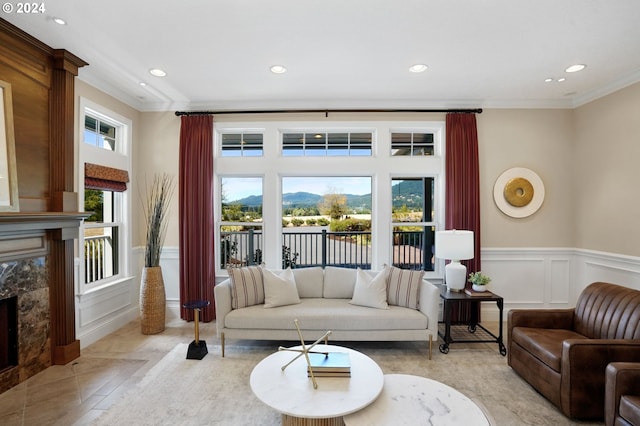 living room with a high end fireplace, a healthy amount of sunlight, crown molding, and a decorative wall