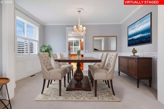 carpeted dining space with a chandelier and ornamental molding