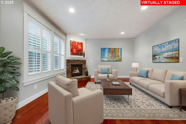 living room featuring a stone fireplace, dark hardwood / wood-style flooring, and a textured ceiling