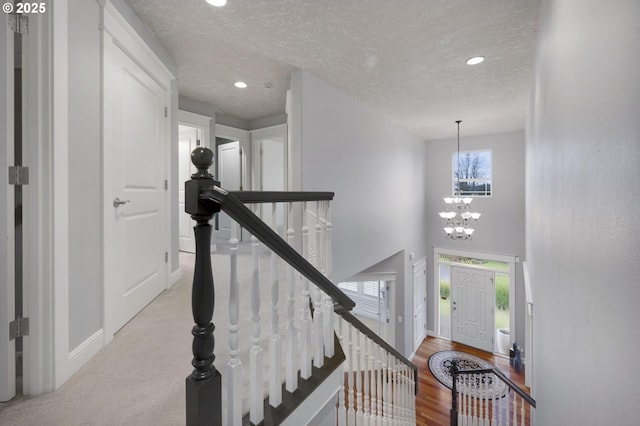 entryway with light hardwood / wood-style flooring, a textured ceiling, a high ceiling, and an inviting chandelier