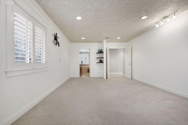 unfurnished room with light colored carpet, a textured ceiling, and ornamental molding