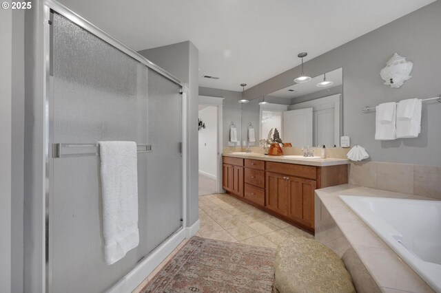 bathroom with vanity, a relaxing tiled tub, and tile patterned floors