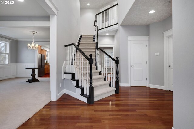 entrance foyer with a chandelier, dark wood-type flooring, and crown molding