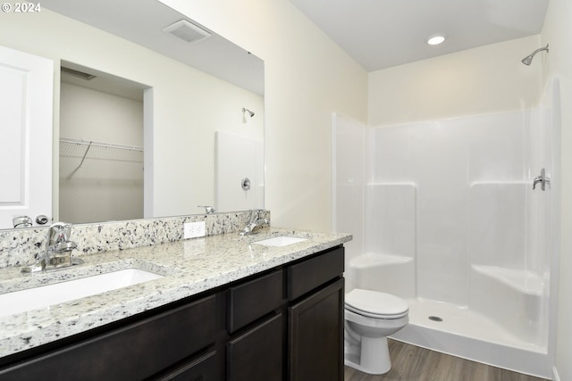 bathroom featuring vanity, hardwood / wood-style floors, a shower, and toilet