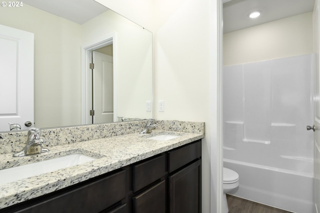 full bathroom with toilet, bathtub / shower combination, hardwood / wood-style floors, and dual bowl vanity