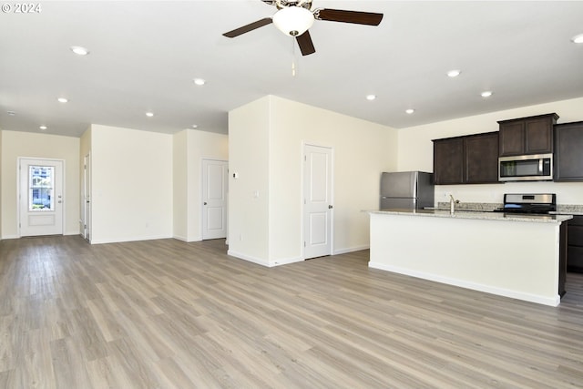 kitchen featuring dark brown cabinetry, a center island with sink, light wood-type flooring, ceiling fan, and stainless steel appliances