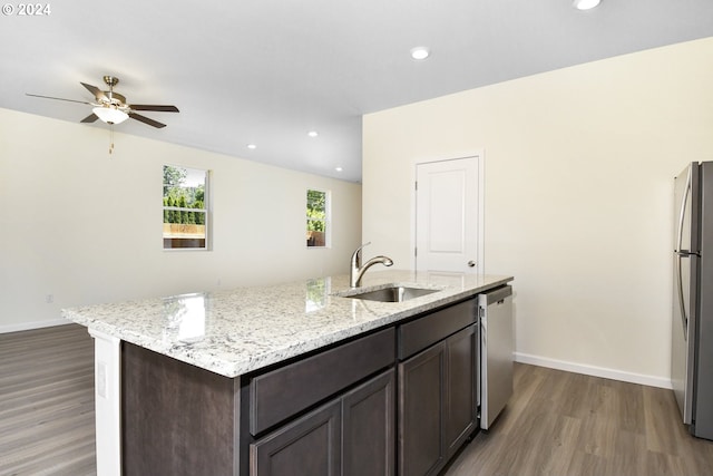 kitchen featuring sink, dark wood-type flooring, dark brown cabinets, stainless steel appliances, and light stone countertops