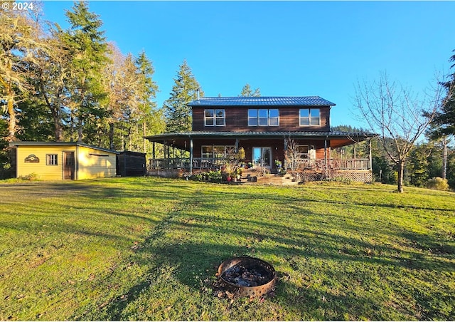 view of front facade with an outbuilding, a front yard, an outdoor fire pit, and covered porch