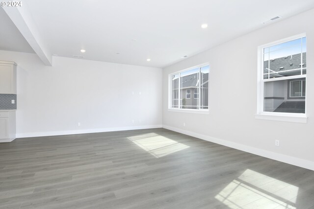 unfurnished room with beamed ceiling and hardwood / wood-style floors