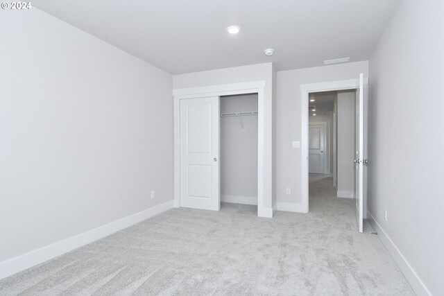 unfurnished bedroom with a closet and light colored carpet