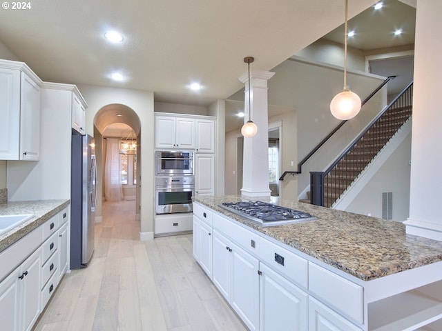 kitchen featuring pendant lighting, a center island, light hardwood / wood-style floors, white cabinetry, and stainless steel appliances