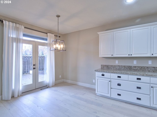 kitchen featuring white cabinets, decorative light fixtures, light hardwood / wood-style flooring, and french doors