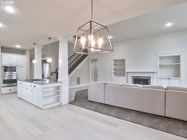 unfurnished living room featuring an inviting chandelier and light hardwood / wood-style flooring