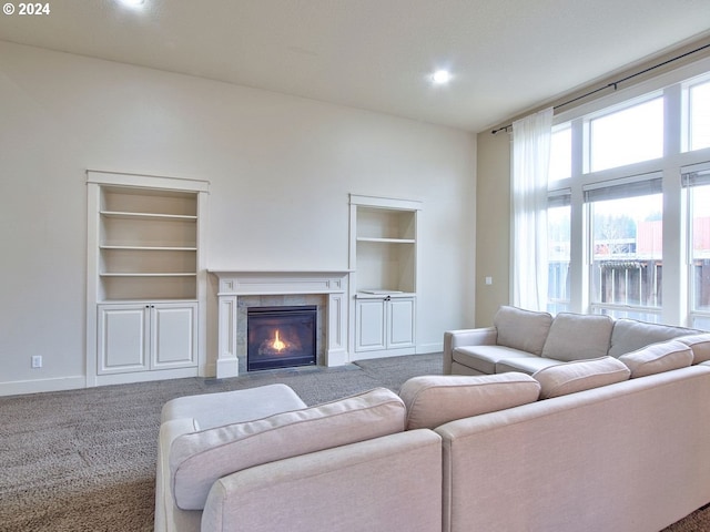 carpeted living room featuring built in shelves and a tiled fireplace