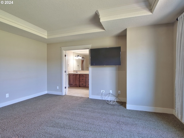 empty room featuring a raised ceiling, light colored carpet, a textured ceiling, and ornamental molding