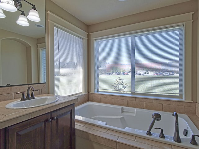 bathroom with vanity and a relaxing tiled tub