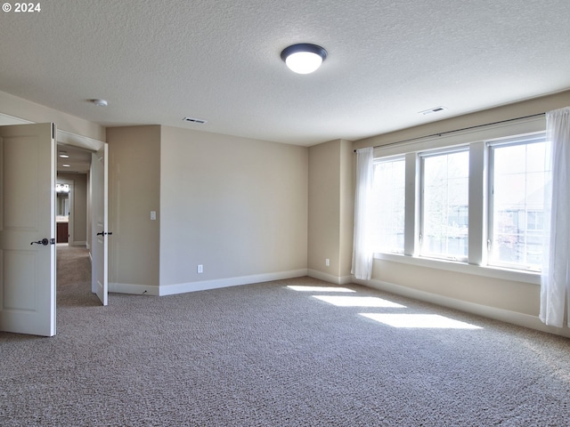 carpeted spare room featuring a textured ceiling