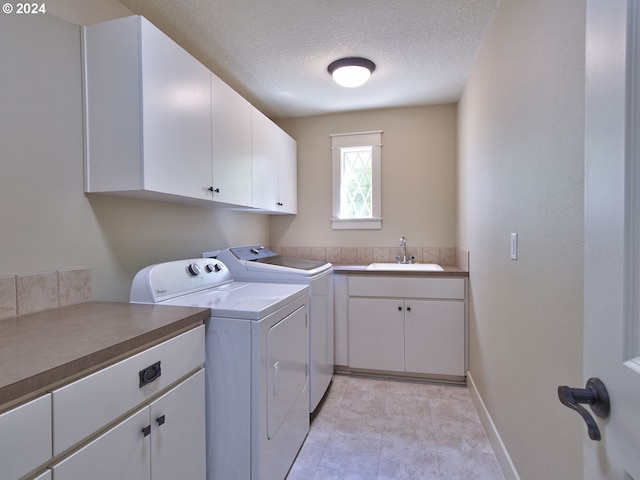 washroom with sink, washer and dryer, cabinets, and a textured ceiling