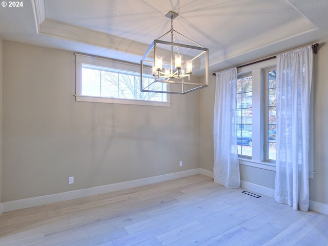 unfurnished dining area featuring a chandelier, crown molding, light hardwood / wood-style flooring, and a tray ceiling