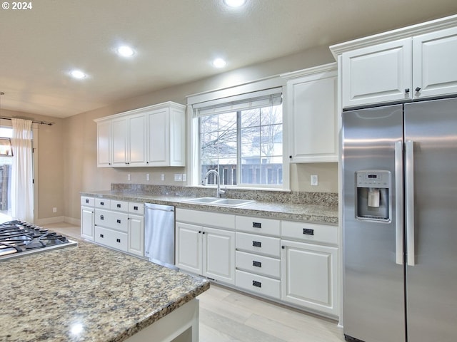 kitchen with white cabinets, sink, light hardwood / wood-style floors, light stone counters, and stainless steel appliances