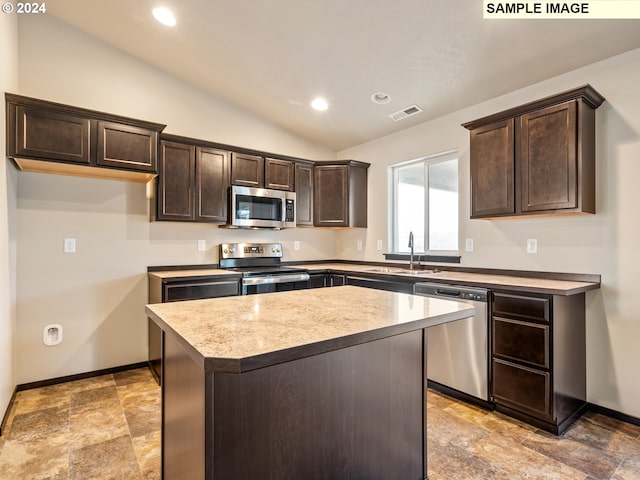 kitchen with a kitchen island, sink, appliances with stainless steel finishes, and vaulted ceiling