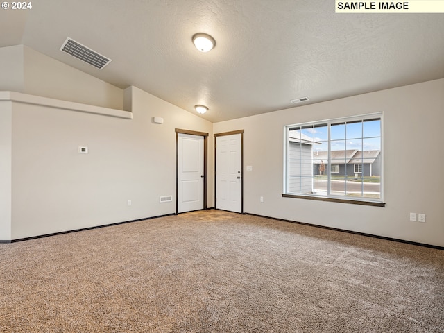 spare room with carpet flooring, a textured ceiling, and vaulted ceiling